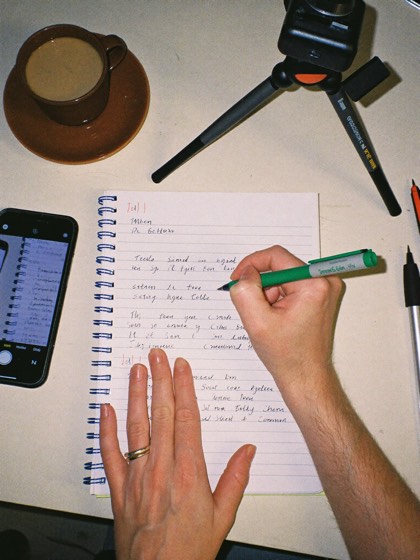 Manos escribiendo el plan de contenido junto al telefono en tripode